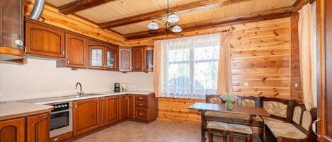 A wooden interior with a kitchen, dining table, and chairs.