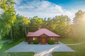A two-story house with a red-tiled roof, a front porch, and a paved driveway leading to the entrance. - Comfortable holiday home with a fireplace (Bobolin)