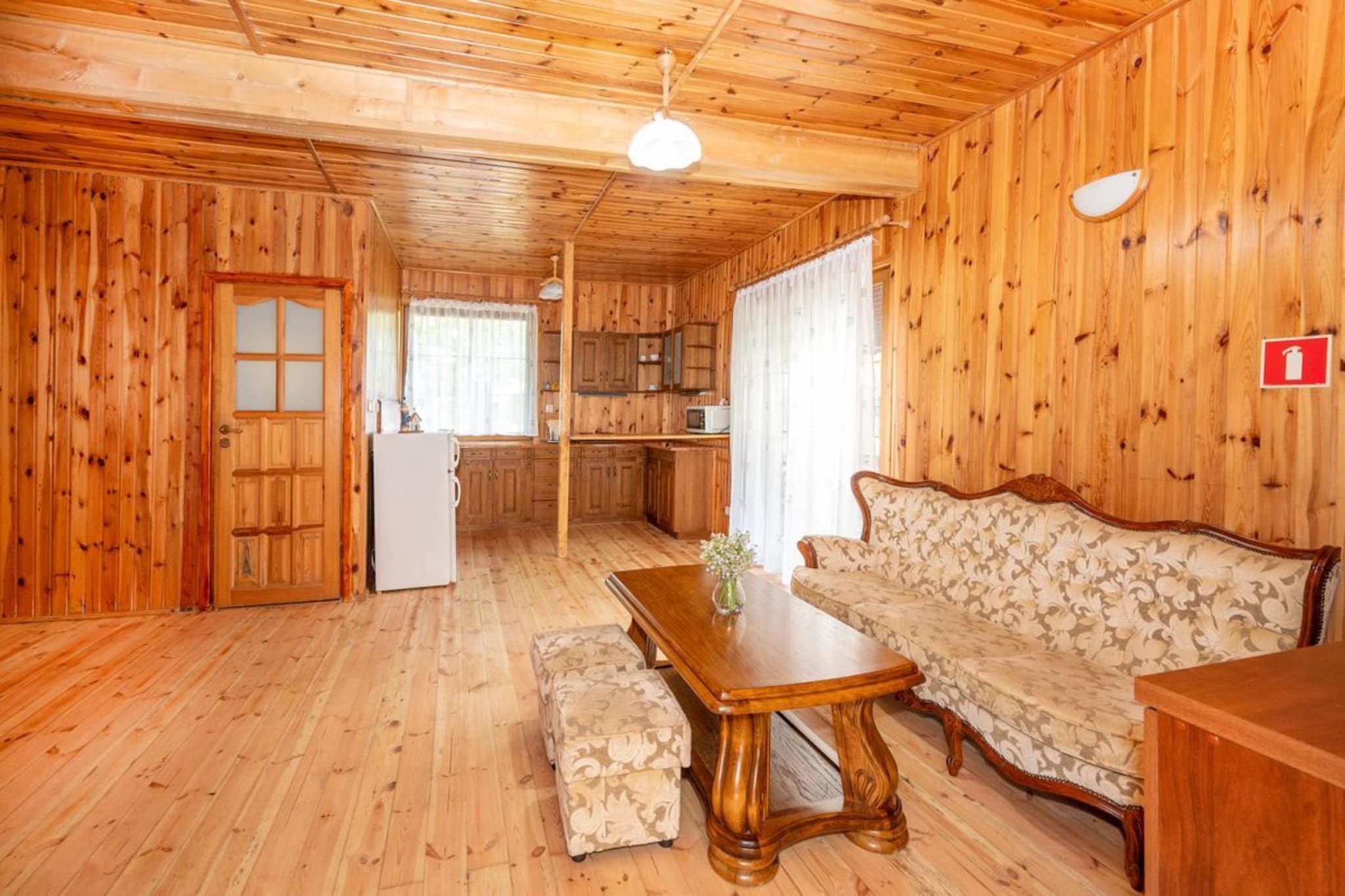Un intérieur en bois comprenant une table à manger, un canapé et un coin cuisine.