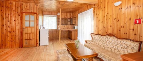 Un interior de madera con una mesa de comedor, sofá y pequeña cocina.