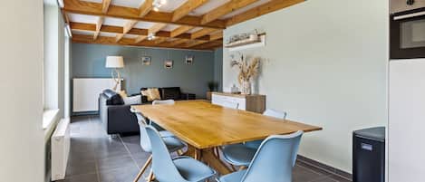 Une cuisine moderne avec une table et des chaises en bois, un four encastré et un coin repas comprenant un canapé et une lampe.