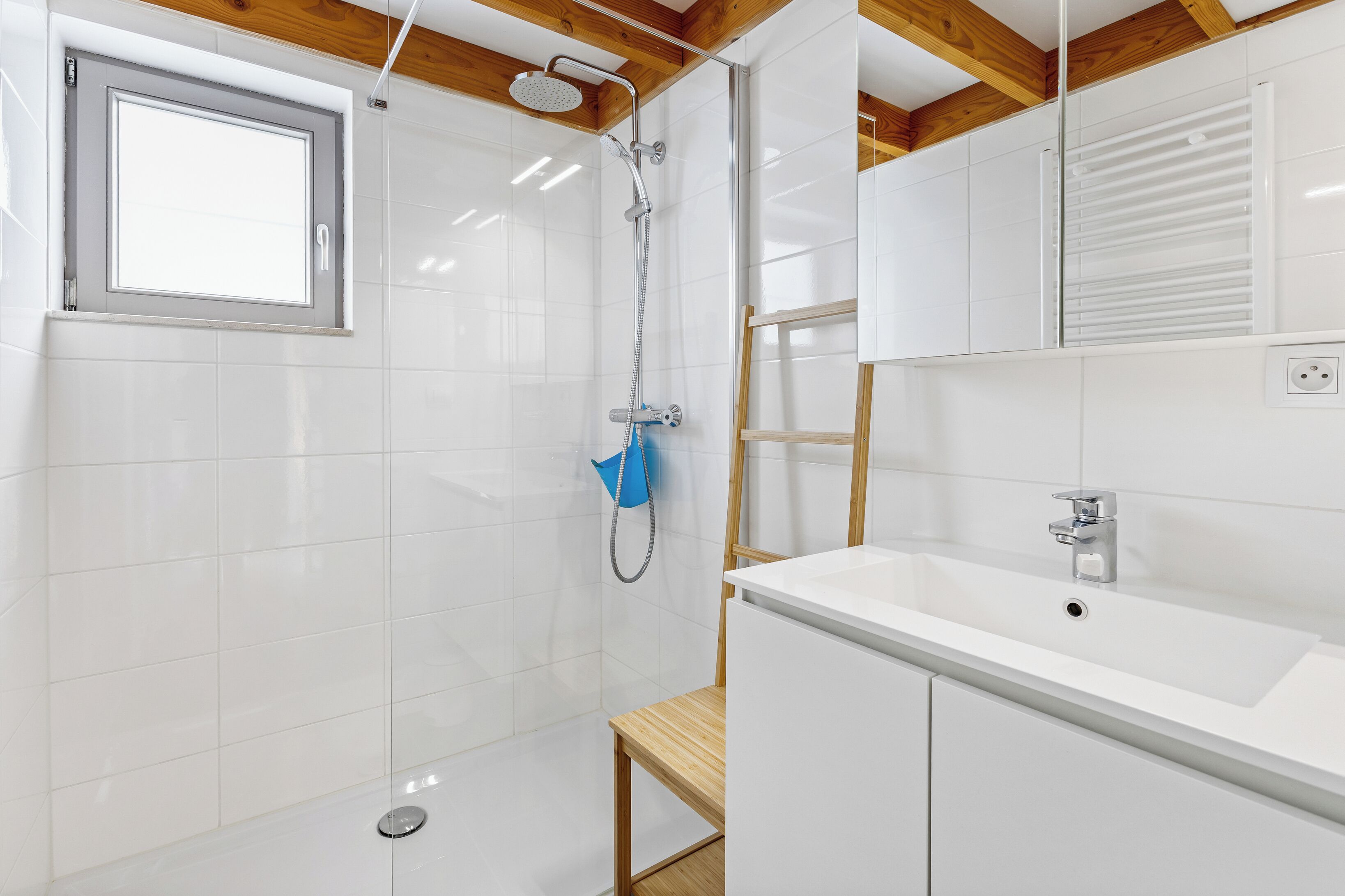 Une salle de bain moderne avec une douche, un lavabo et une fenêtre.