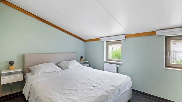 Una camera da letto con un letto, comodini, una finestra e un termosifone.