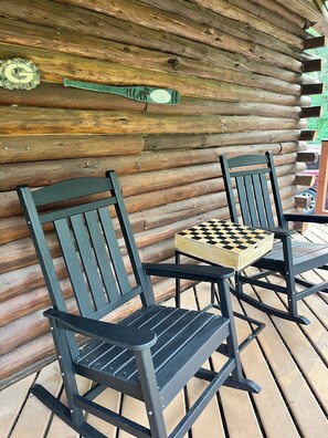 Zwei Schaukelstühle mit einem Schachbrettspiel auf einer Holzterrasse.