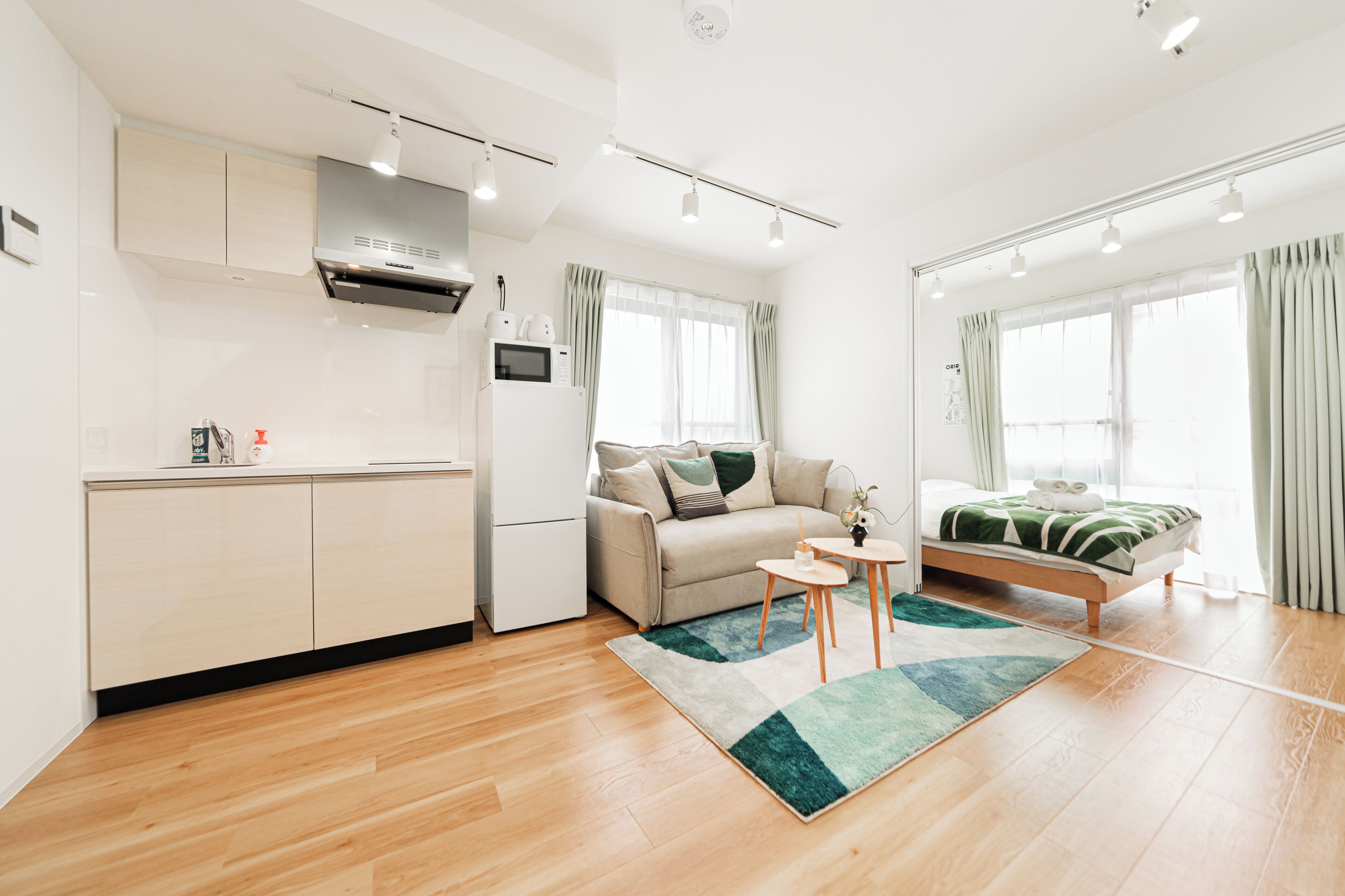 A modern apartment with a kitchenette, a sofa, a bed, and a small table.