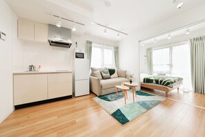 A modern apartment with a kitchenette, a sofa, a bed, and a small table. - Toka Art Hotel (Taito)