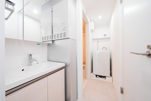 Ein modernes Badezimmer mit einem weißen Waschbecken, einem Chromarmaturen und einem Spiegel darüber.