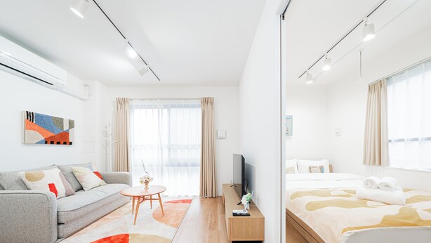 Habitació d'hotel moderna amb un sofà, un llit, una televisió i una taula petita.