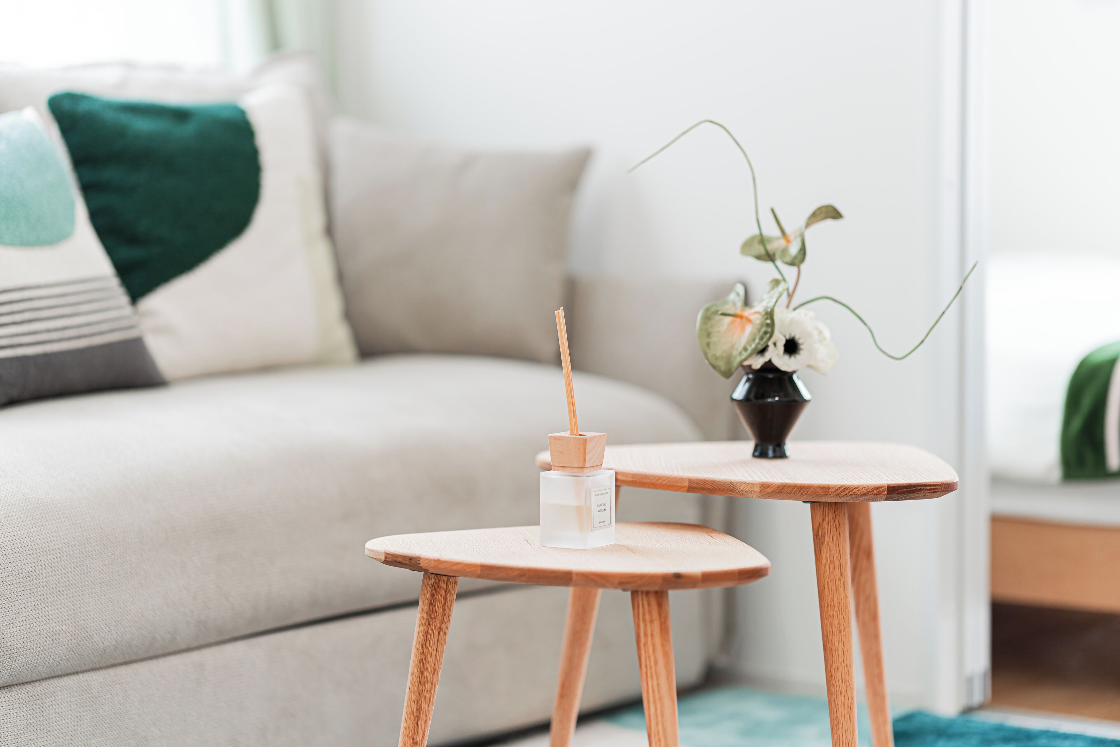Un salon moderne avec un canapé, une petite table d’appoint en bois et un vase rempli de fleurs.