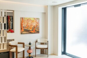 A modern living room with a large window, a bookshelf, and a painting. - Toka Art Hotel (Taito)