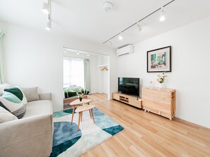 Ein modernes Wohnzimmer mit einer Couch, einem Fernseher, einem Holzschrank und einem blauen Teppich.