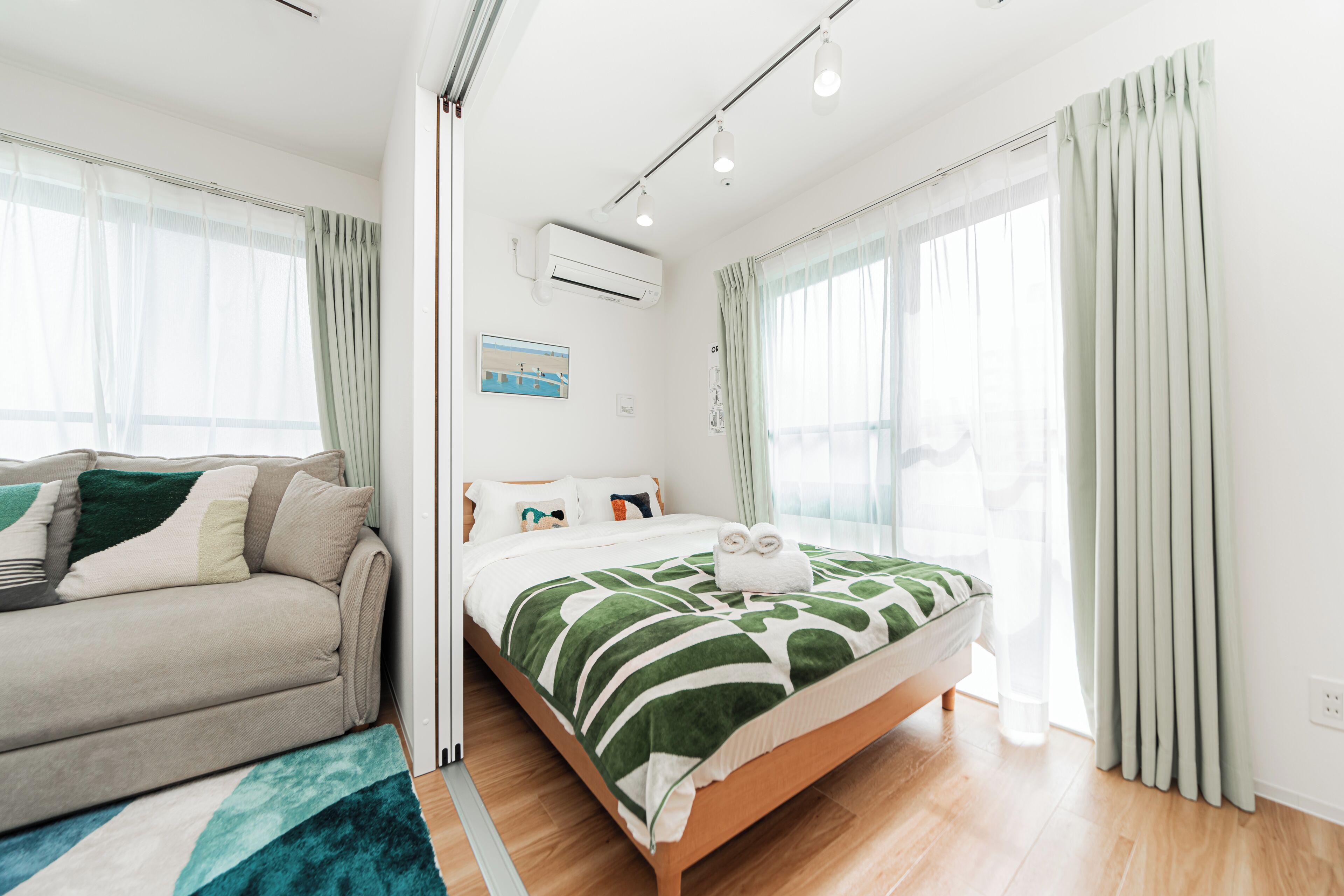 Une chambre à coucher moderne avec un lit, un canapé et une grande fenêtre.