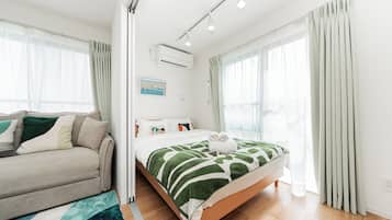 A modern bedroom with a bed, a sofa, and a large window.