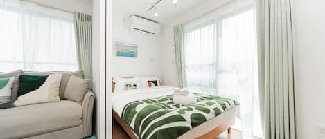 A modern bedroom with a bed, a sofa, and a large window.