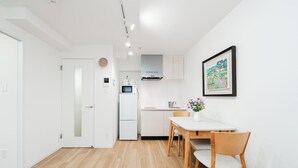 Una cuina moderna amb electrodomèstics blancs, una zona de menjador amb taula i cadires, i un quadre al mur.