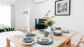A neatly arranged dining area with a table set for four, a television, and a framed artwork on the wall.