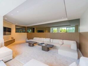 Ein modernes Wohnzimmer mit einem Ecksofa, einem Couchtisch und einem eingebauten Fernseher.