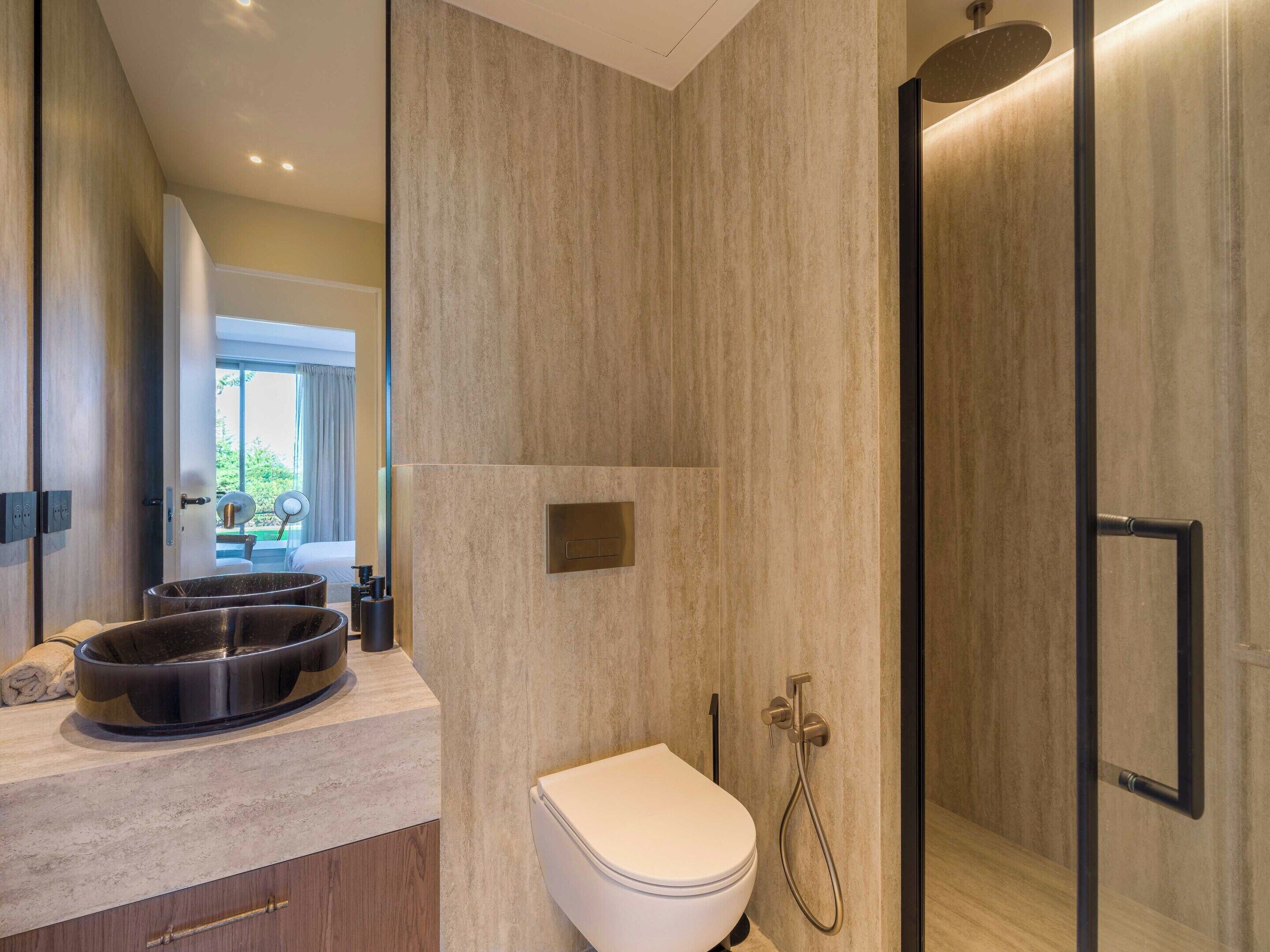 Une salle de bain moderne équipée de toilettes, d’un bidet et d’une douche.