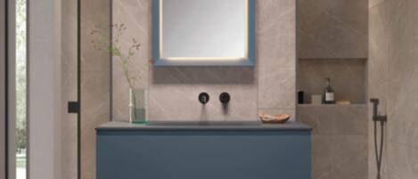 Un baño moderno con lavamanos integrado, un espejo y zona de ducha.