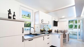 Una cocina moderna con armarios blancos, una estufa integrada y un ventanal grande.