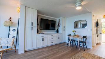 A modern kitchen with white cabinets, a dining table with chairs, and a ceiling fan.