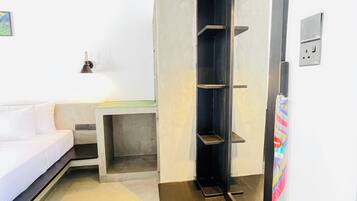 A modern bathroom with a shower, a toilet, and a sink. There is a white wall with a power outlet and a light switch.