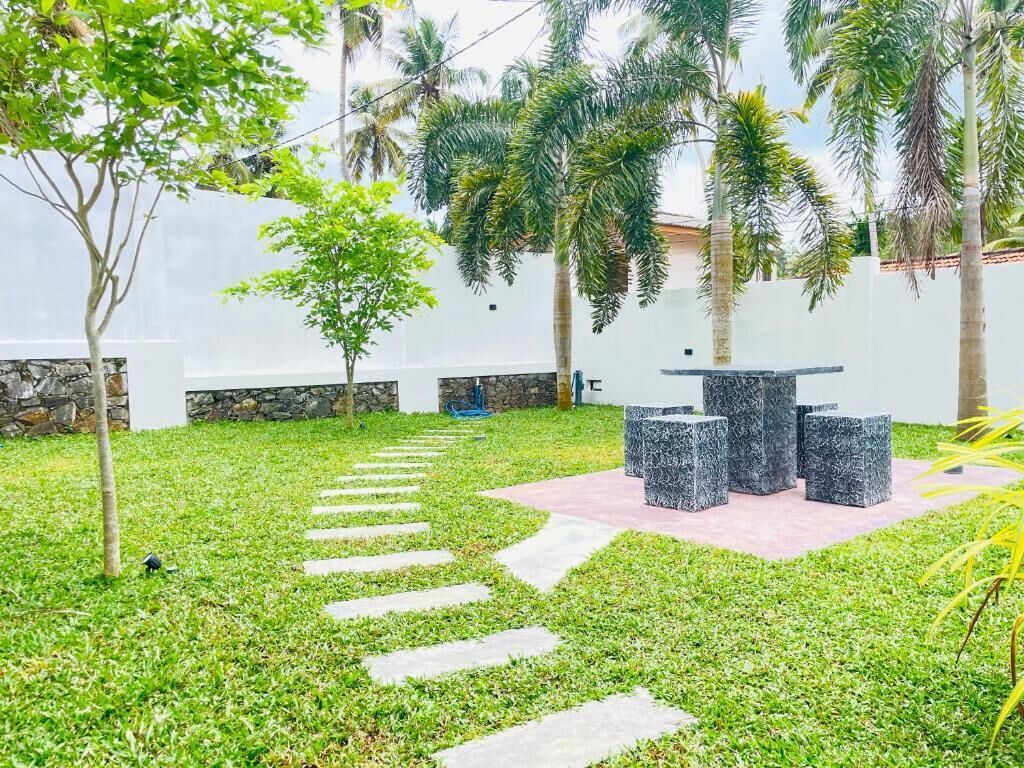 Un patio con un camino de piedra que lleva a una zona de estar con una mesa y sillas.