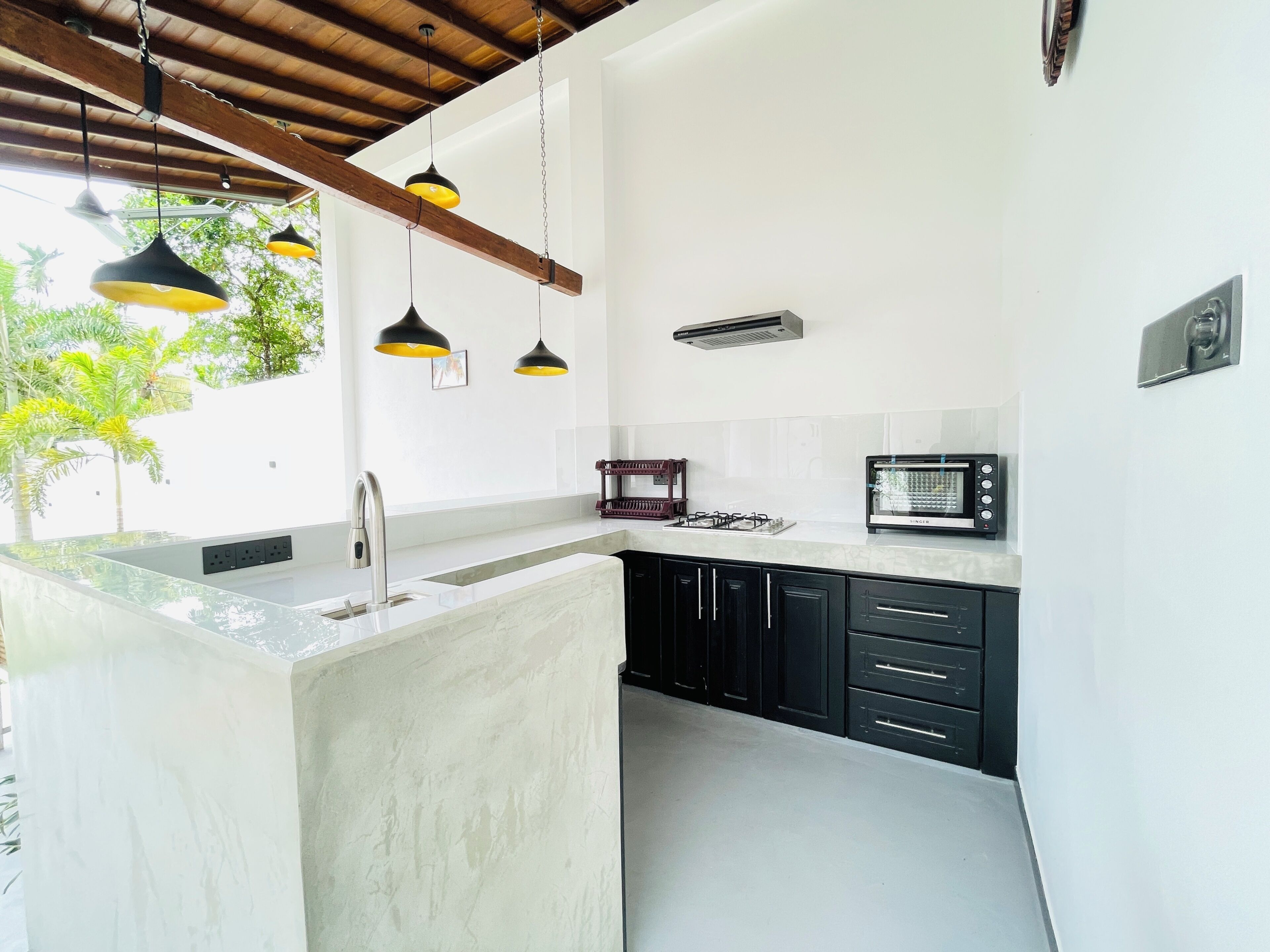 Una cocina moderna con una isla central, armarios negros, microondas e iluminación colgante.