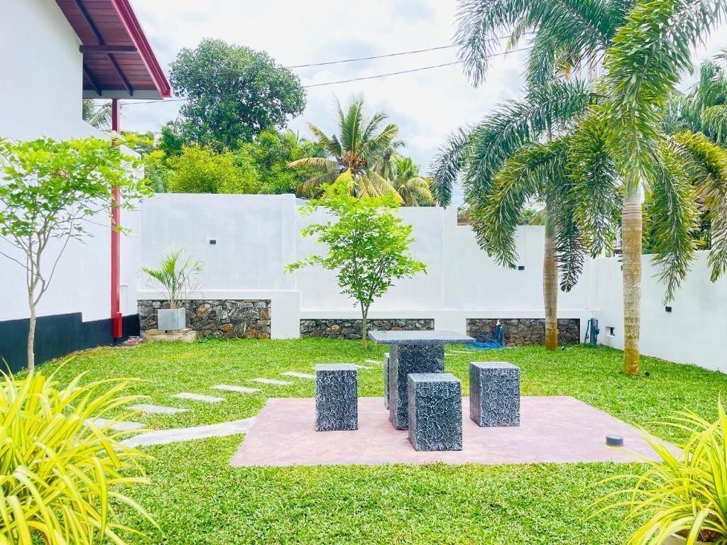 A courtyard with a seating area, palm trees, and a white building.