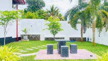 A courtyard with a seating area, palm trees, and a white building.