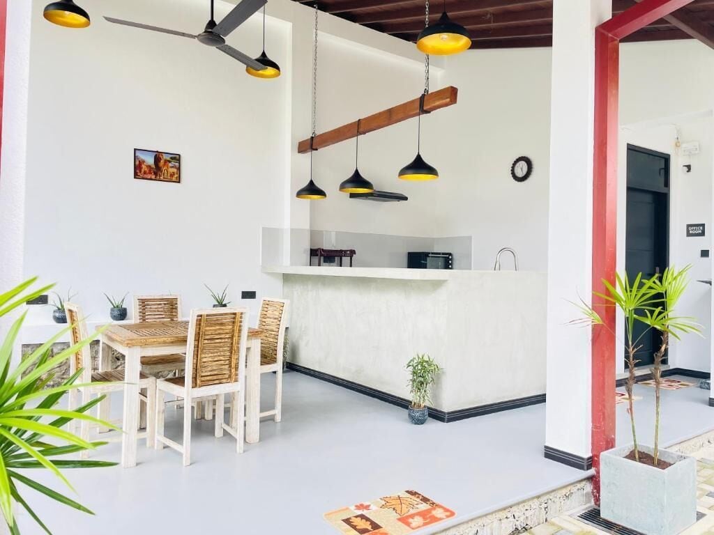 A dining area with a white table and chairs, a ceiling fan, pendant lights, and a small potted plant.