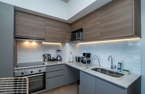 A modern kitchen with built-in appliances, a stainless steel sink, and a compact layout. - Corporate Stays Hassler - 105 (Asunción)
