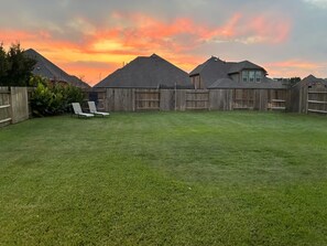 Ein Garten mit Holzzaun, Rasen und Sonnenuntergangshimmel.