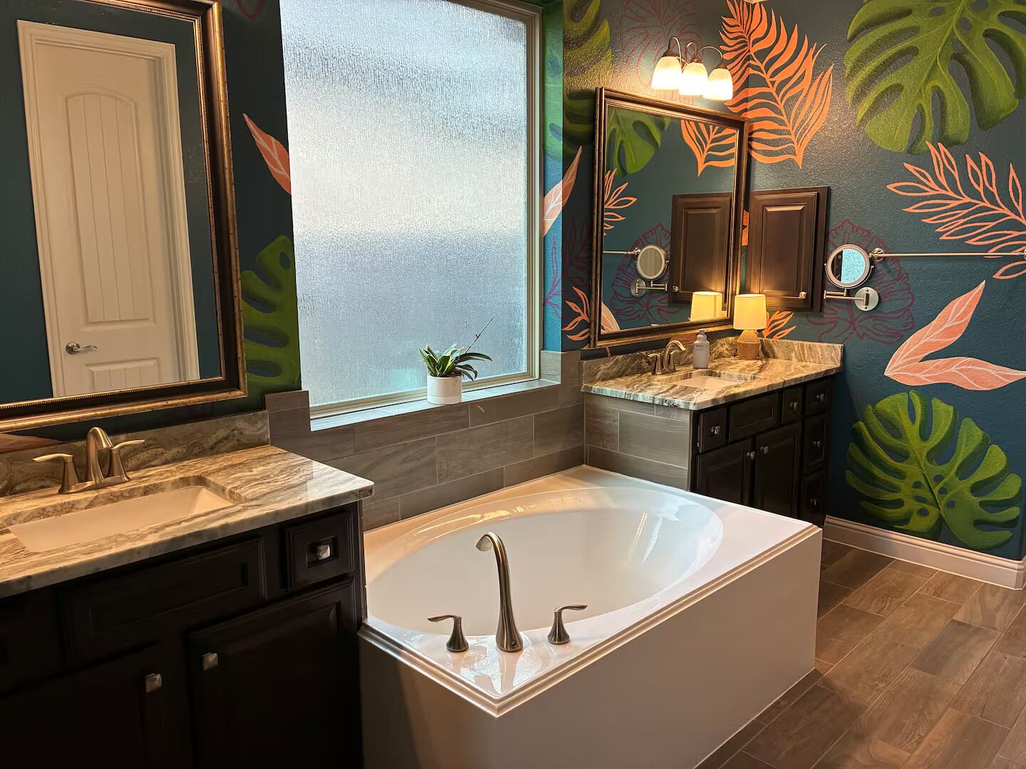 A modern bathroom with a large bathtub, two sinks, and a window.