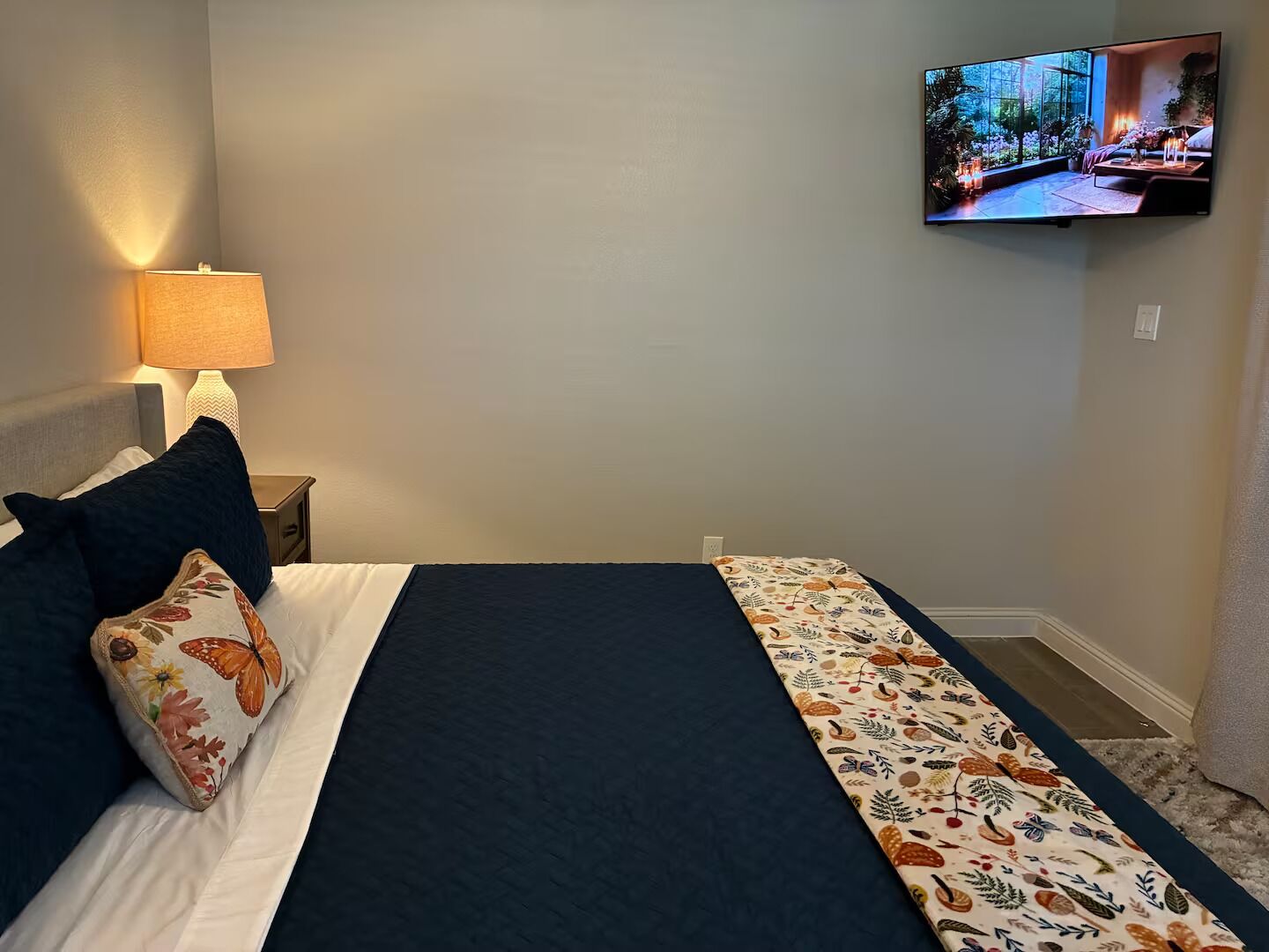 Une chambre d’hôtel équipée d’un lit, d’une table de chevet, d’une lampe et d’un téléviseur fixé au mur.