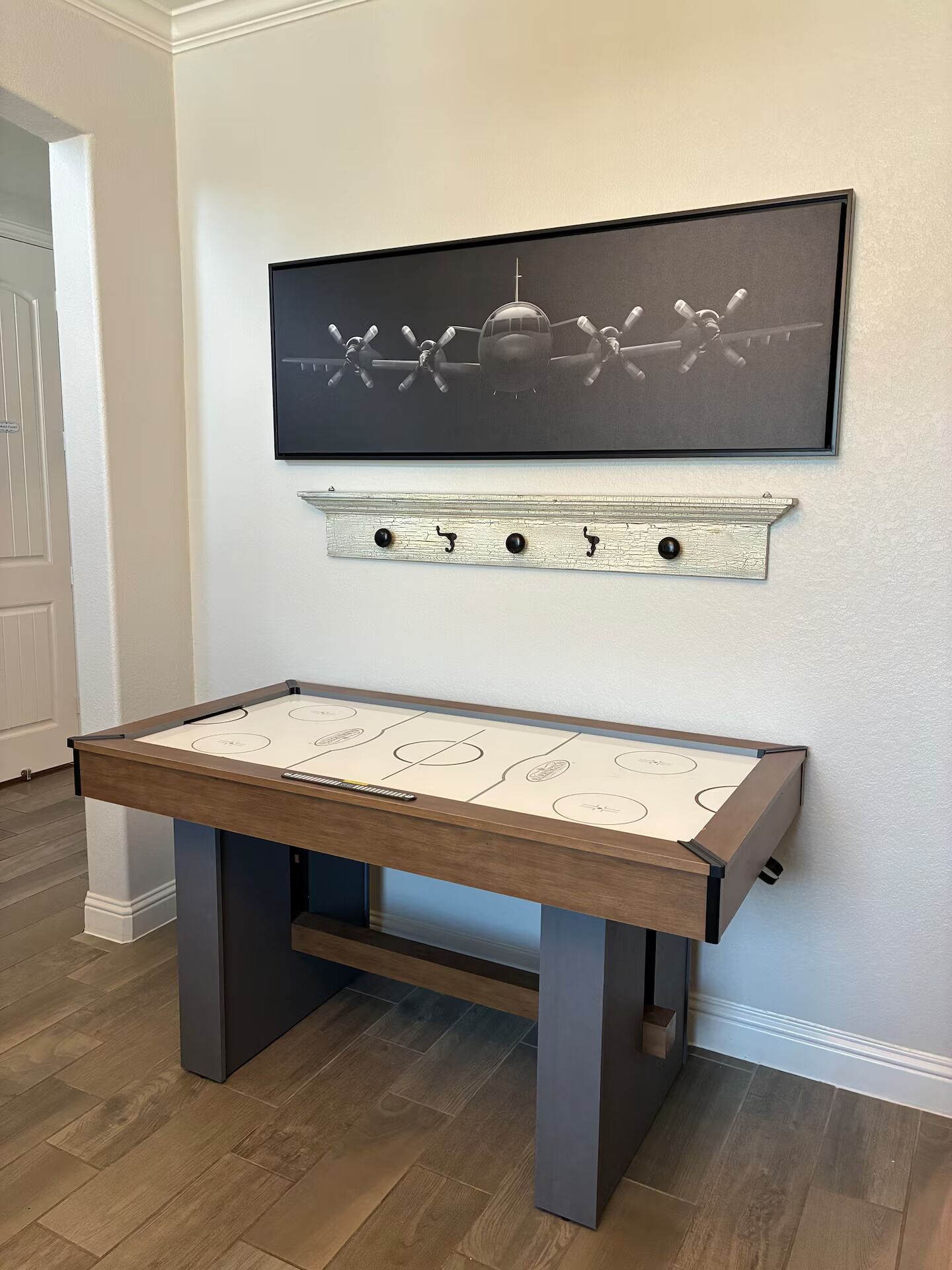 A room with a foosball table, a framed artwork above it, and a decorative shelf below.
