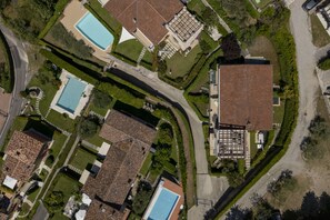 Eine Vogelperspektive auf ein Wohngebiet mit mehreren Häusern, einem Schwimmbad und einer gepflasterten Straße.
