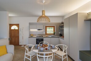 A modern kitchen with a dining area, a wooden door, and a window. - Towerhill Apartment with Roofterrace and shared Po (Torri del Benaco)