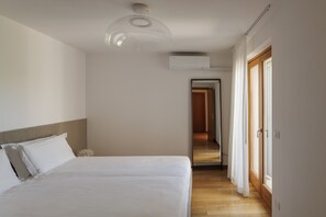 A hotel room with a bed, a ceiling light fixture, an air conditioning unit, and a view of the hallway. - Towerhill Apartment with Roofterrace and shared Po (Torri del Benaco)
