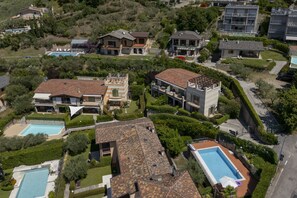 A residential area with multiple houses, some with swimming pools, surrounded by greenery and hills. - Towerhill Apartment with Roofterrace and shared Po (Torri del Benaco)