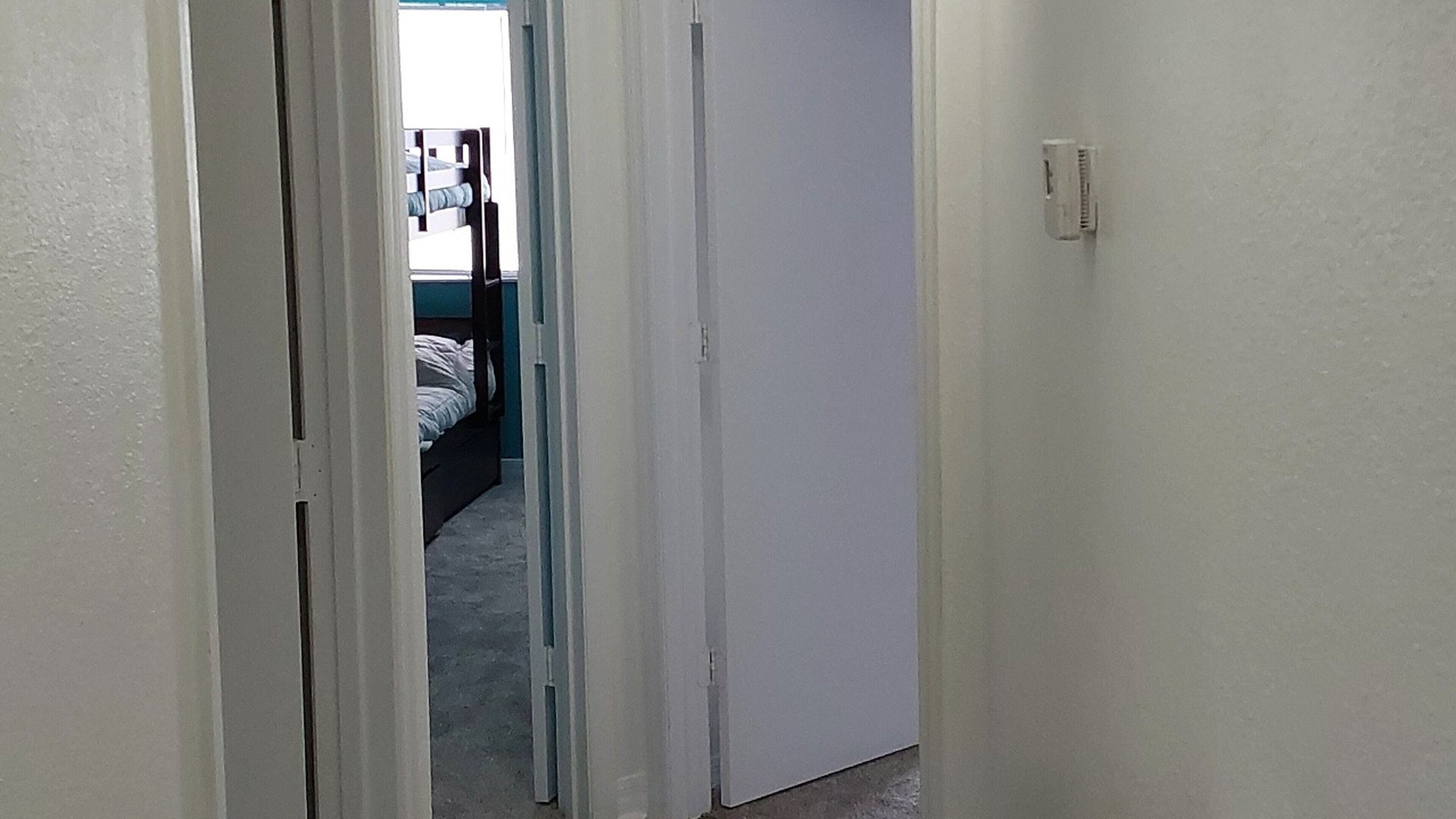 A narrow hallway with a door leading to a bedroom.