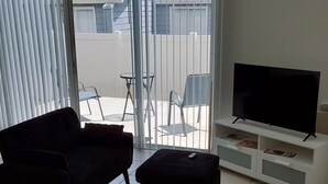 Ett vardagsrum med en soffa, ett soffbord, ett TV-bord och en skjutdörr i glas som leder ut till en balkong.
