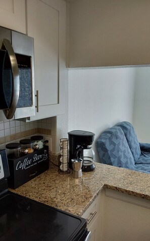 A kitchen with a coffee machine, a coffee bar, and a microwave. - Perfect Getaway Near Disney & Universal (Davenport)