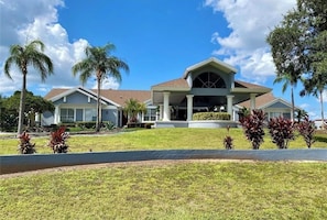 A two-story house with a covered porch, palm trees, and a well-maintained lawn. - Perfect Getaway Near Disney & Universal (Davenport)