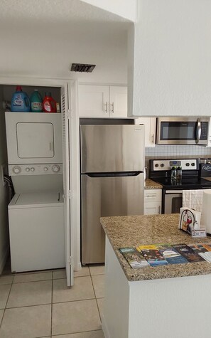 Eine kleine Küche mit Kühlschrank, Mikrowelle und Kaffeemaschine auf der Arbeitsfläche.
