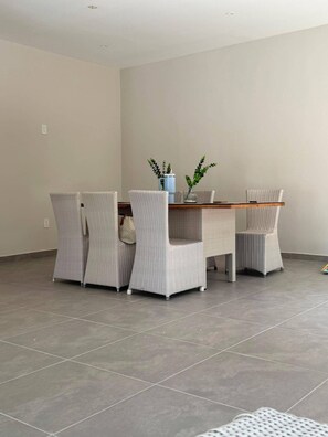 A dining area with a table and four chairs, a vase with plants, and a tiled floor. - Modern 3BR Apartment Central Curaçao Near Beaches (Willemstad)
