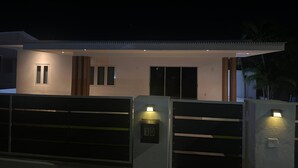 Una casa moderna amb entrada tancada per reixa, garatge i façana ben il·luminada.