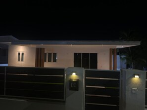 A modern house with a gated entrance, a garage, and a well-lit facade. - Modern 3BR Apartment Central Curaçao Near Beaches (Willemstad)