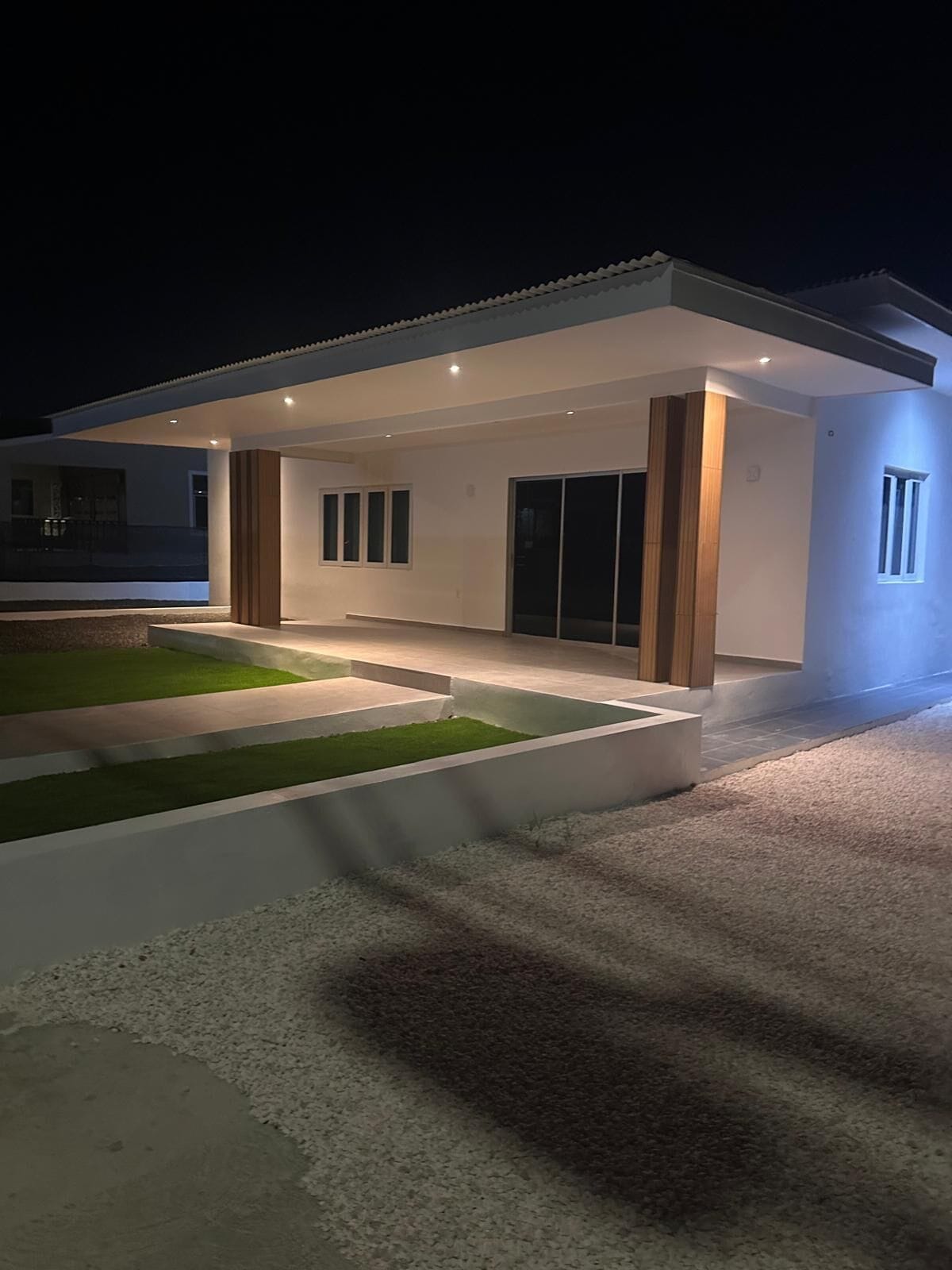 A modern house with a covered patio, a well-maintained lawn, and a gravel driveway.