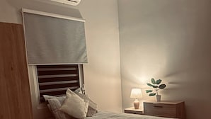 Un dormitori amb un llit, una taula de nit, una làmpada i un aparell d'aire condicionat.